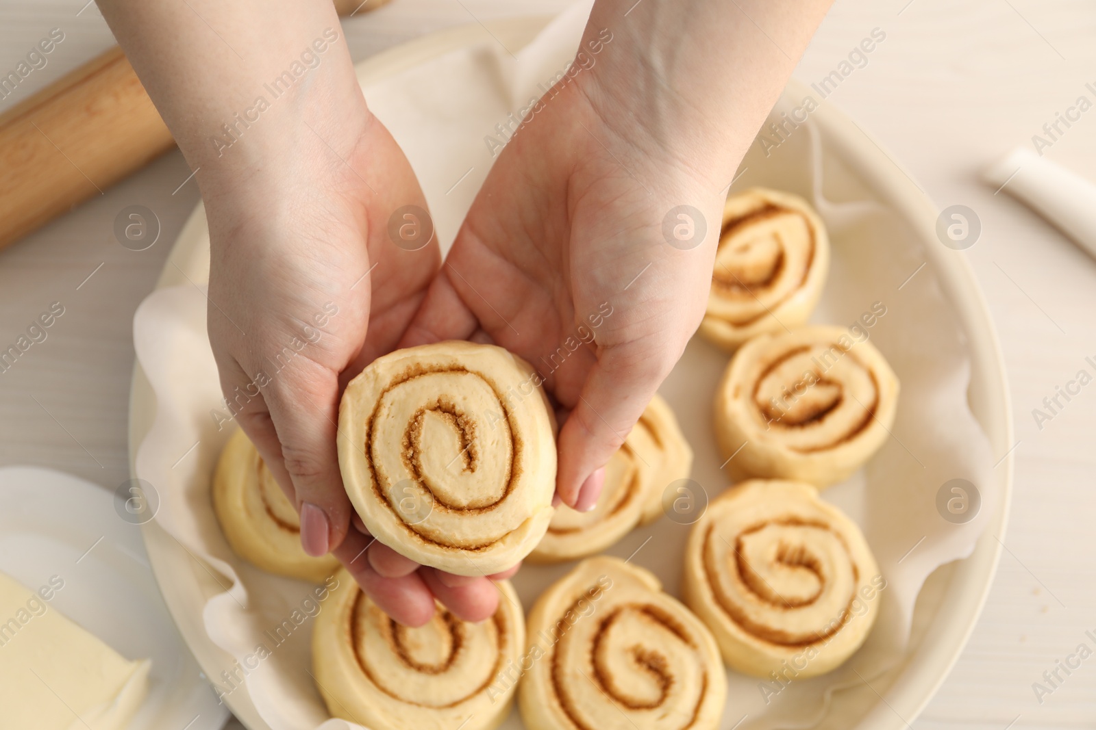 Photo of Woman making cinnamon rolls at white table, top view