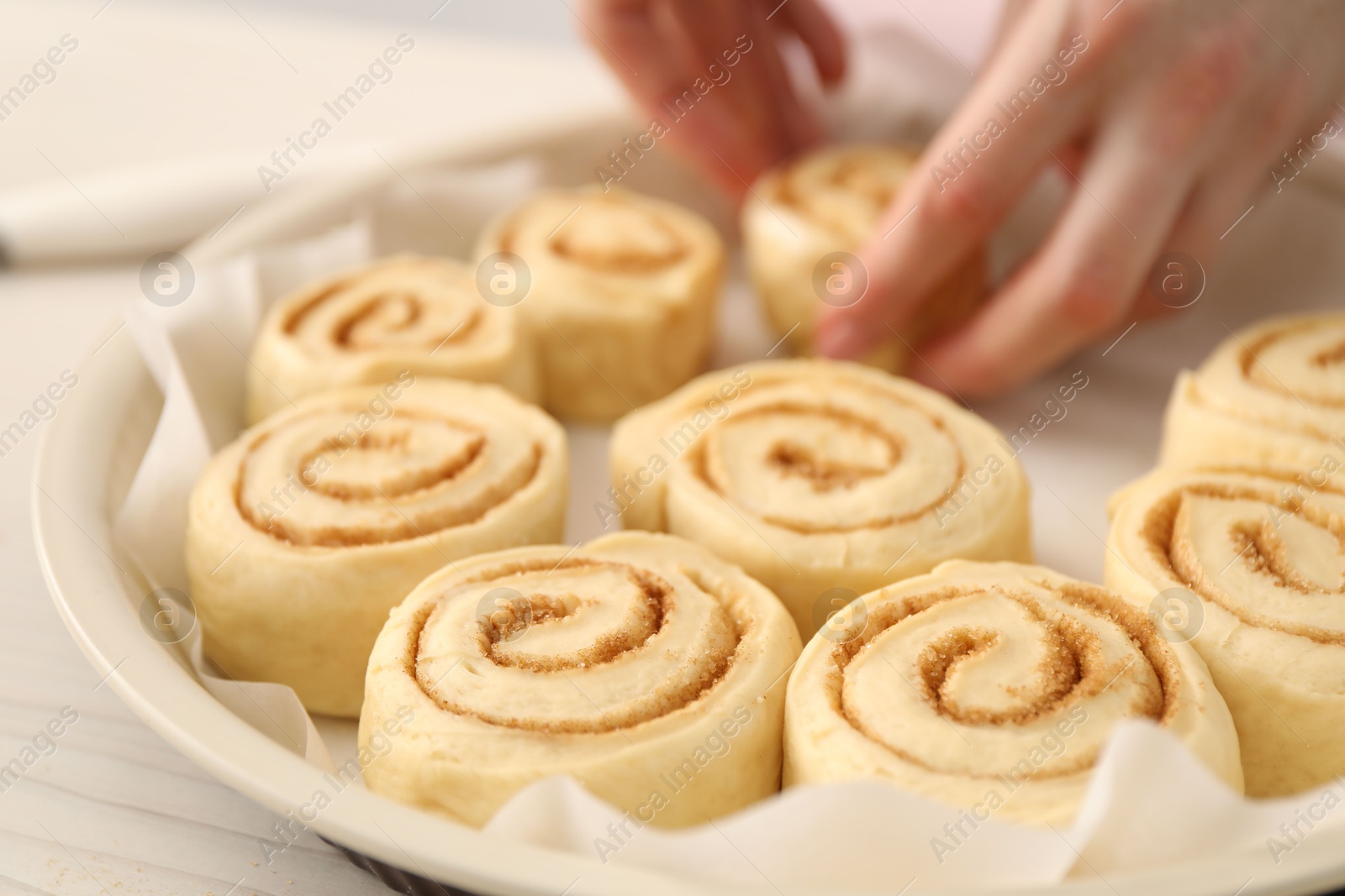 Photo of Woman making cinnamon rolls at table, closeup