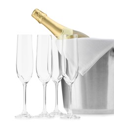 Photo of Bottle of champagne in ice bucket and empty glasses isolated on white