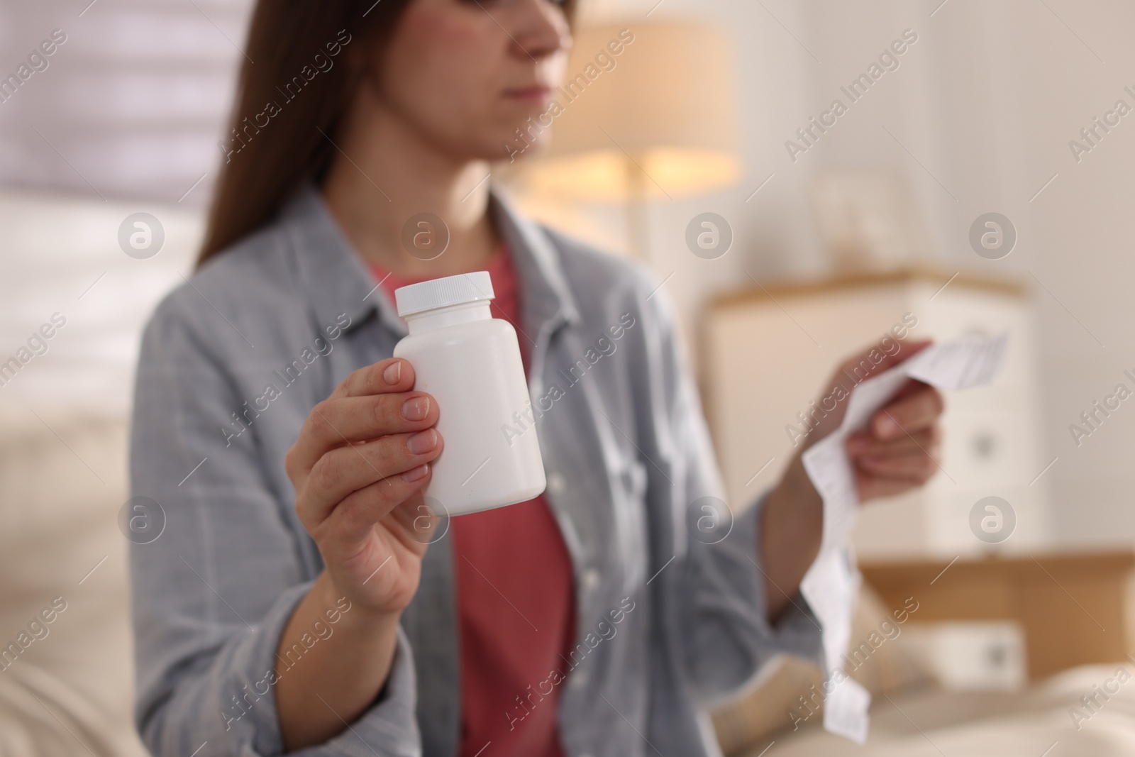 Photo of Woman with pills reading instruction at home, selective focus