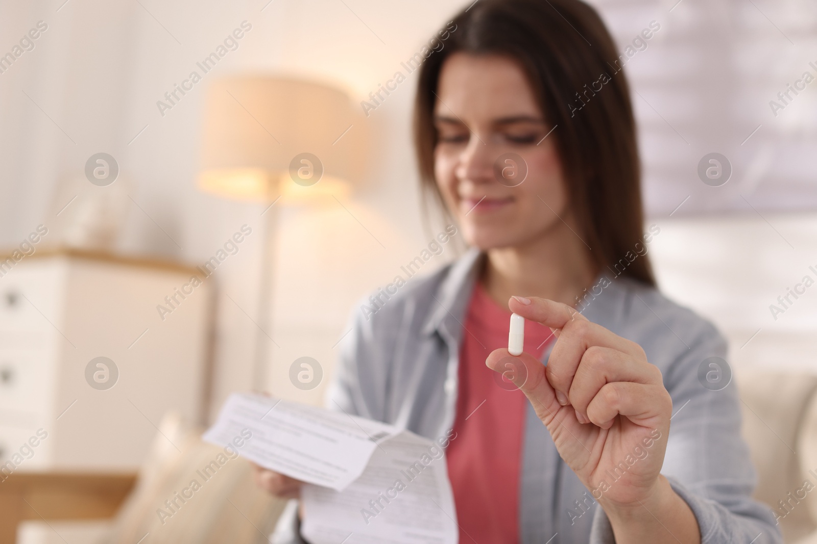 Photo of Woman with pill reading instruction at home, selective focus