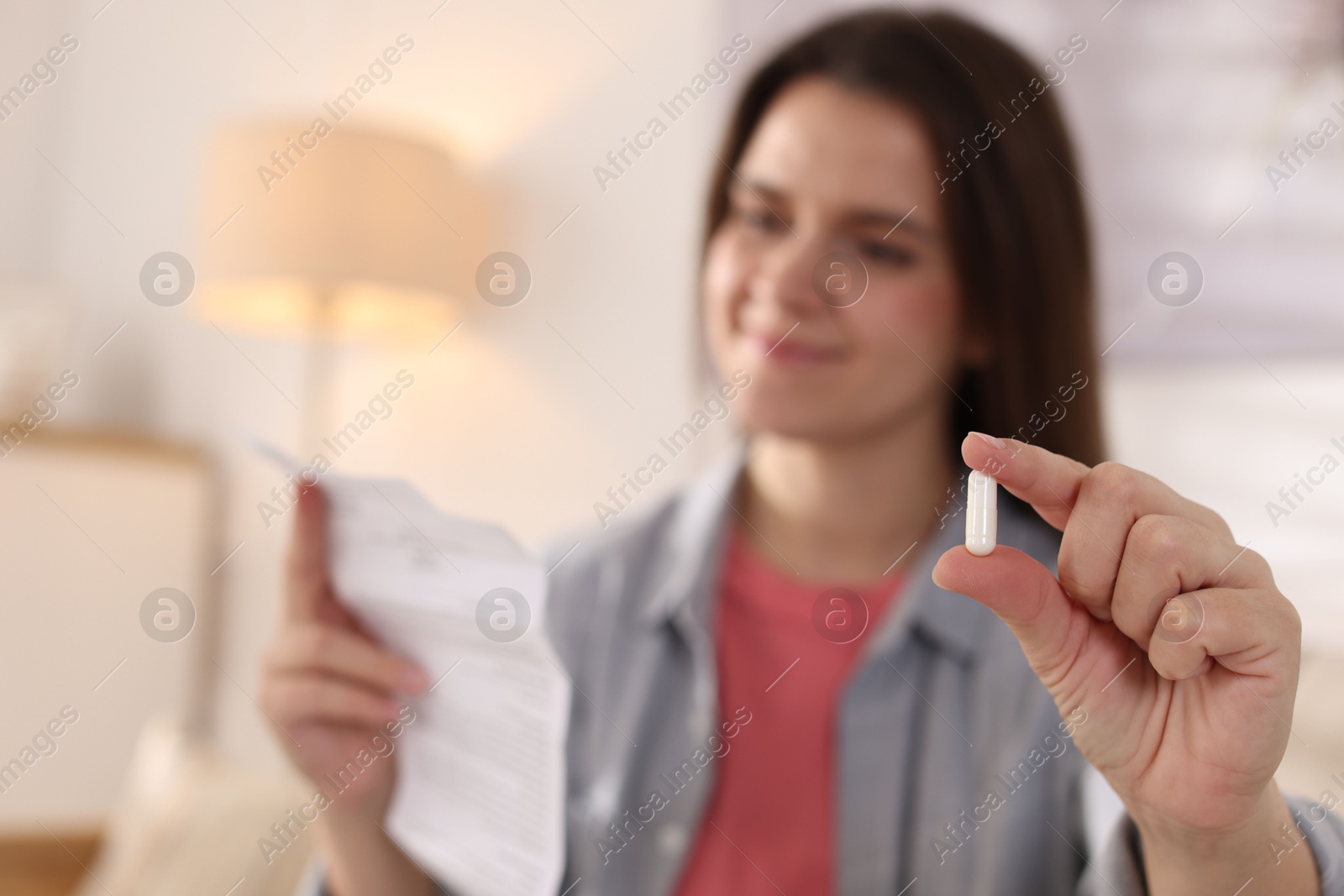 Photo of Woman with pill reading instruction at home, selective focus