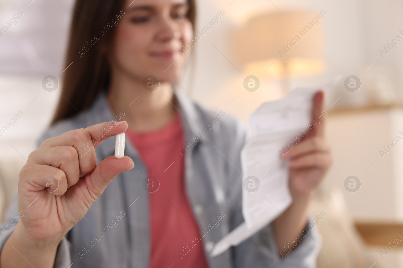 Photo of Woman with pill reading instruction at home, selective focus