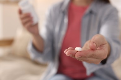 Photo of Woman with pill reading instruction at home, selective focus