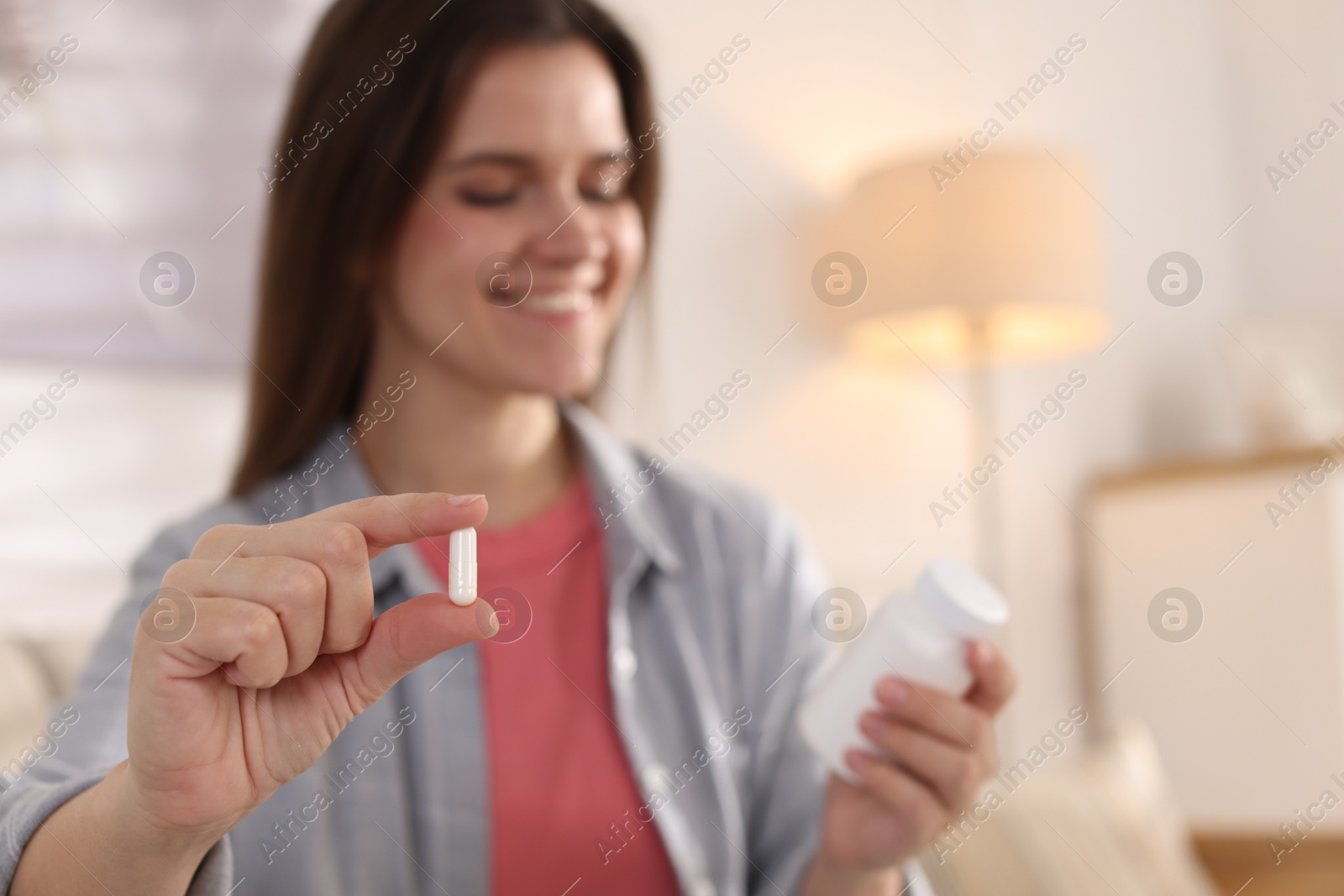 Photo of Woman with pill reading instruction at home, selective focus