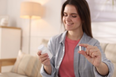 Woman with pill reading instruction at home, selective focus