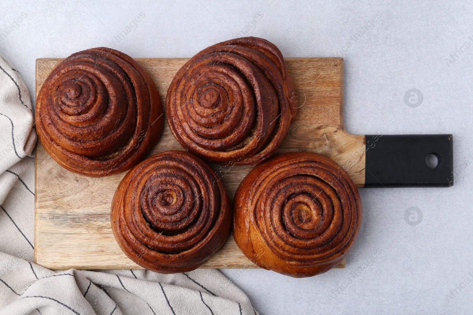 Photo of Delicious cinnamon roll buns on light table, top view