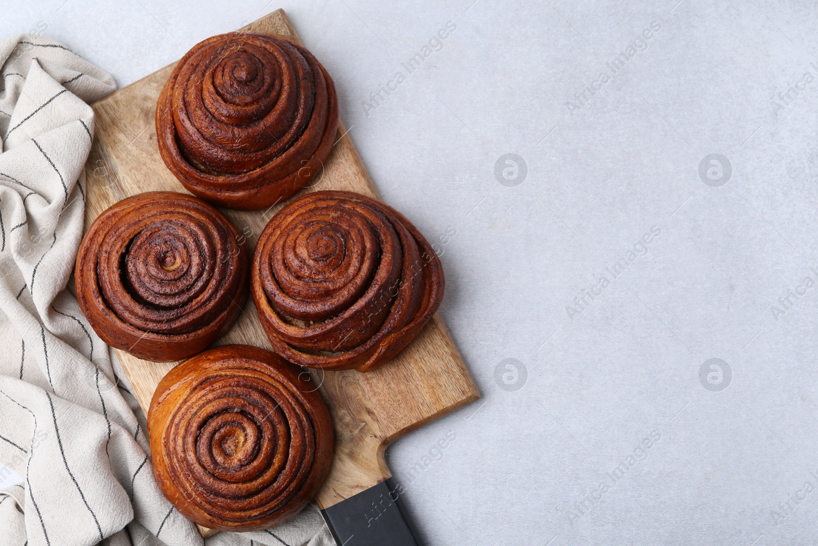 Photo of Delicious cinnamon roll buns on light table, top view. Space for text