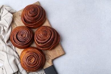 Photo of Delicious cinnamon roll buns on light table, top view. Space for text