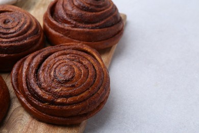 Photo of Delicious cinnamon roll buns on light table, closeup. Space for text