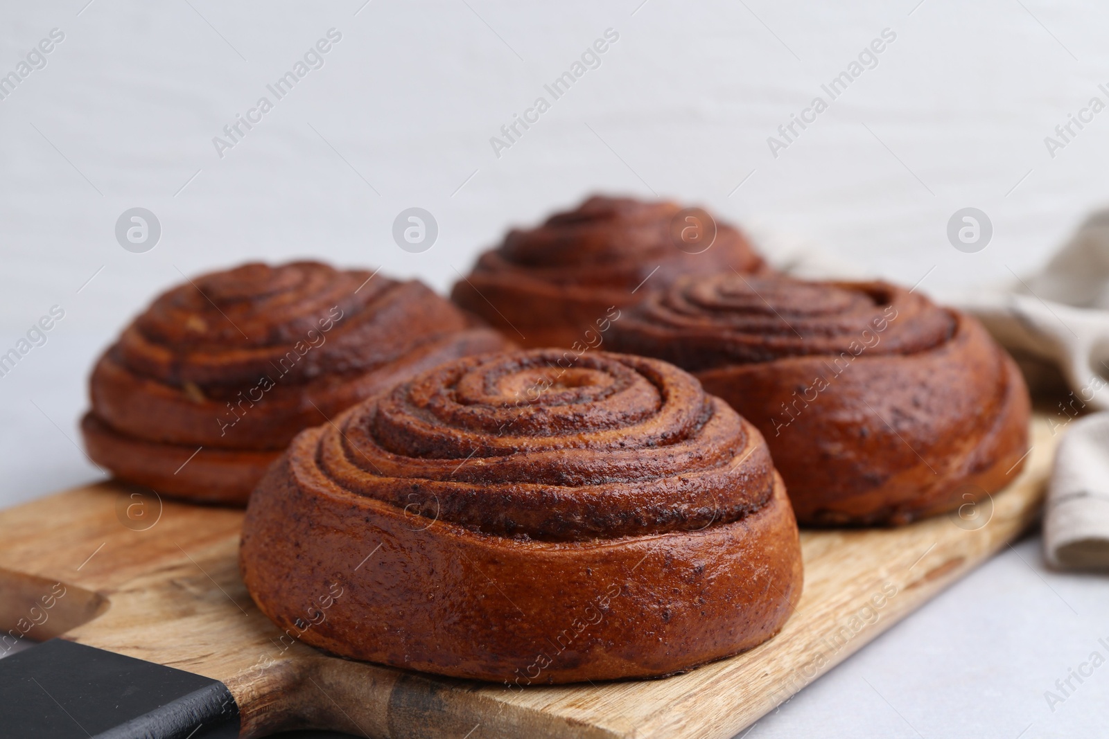 Photo of Delicious cinnamon roll buns on light table, closeup