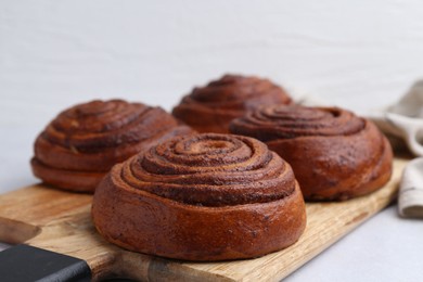 Photo of Delicious cinnamon roll buns on light table, closeup