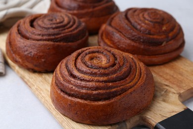 Photo of Delicious cinnamon roll buns on light table, closeup