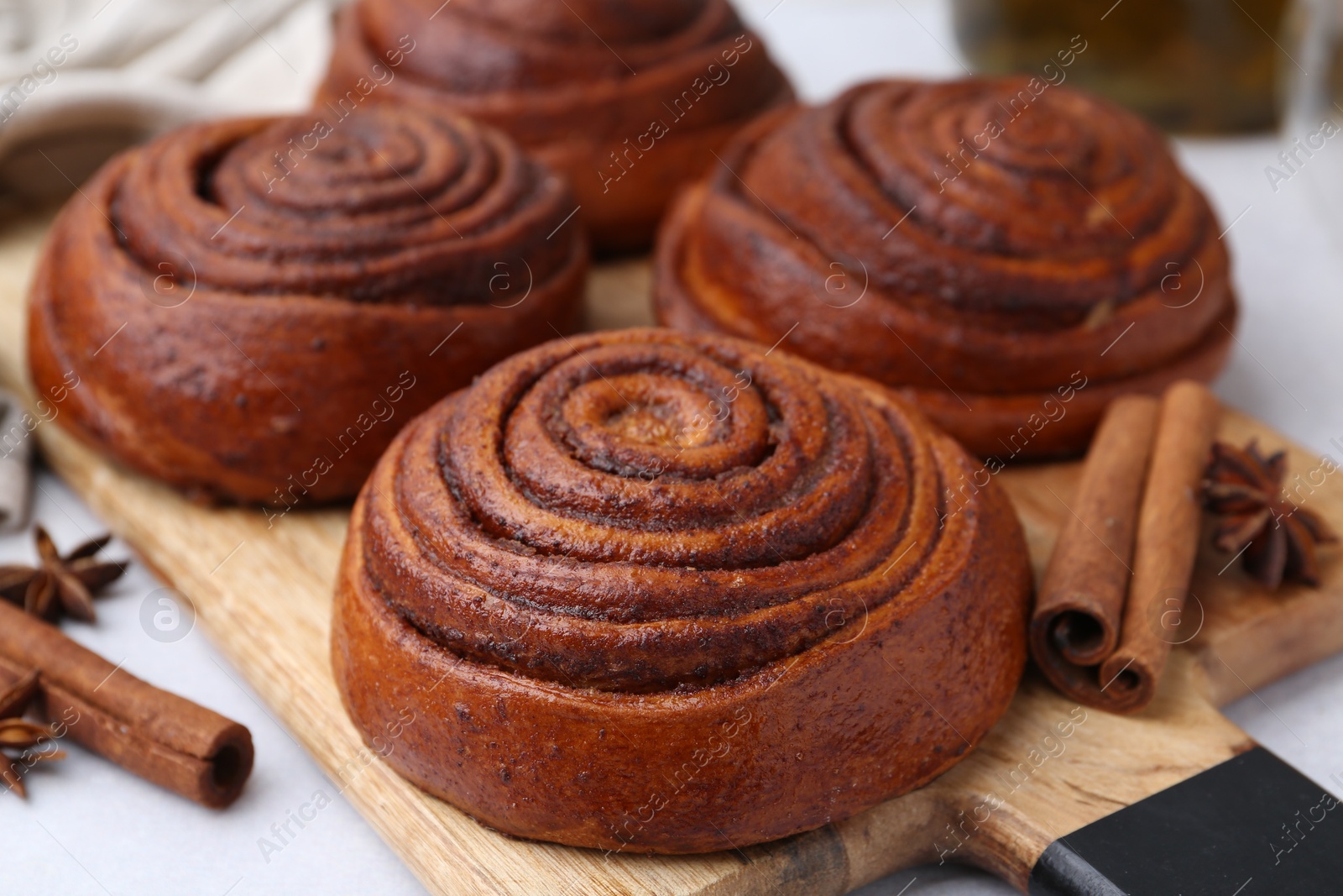 Photo of Delicious cinnamon roll buns on light table, closeup