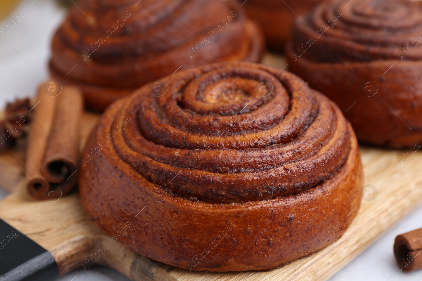 Photo of Delicious cinnamon roll buns on light table, closeup