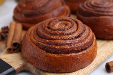 Photo of Delicious cinnamon roll buns on light table, closeup