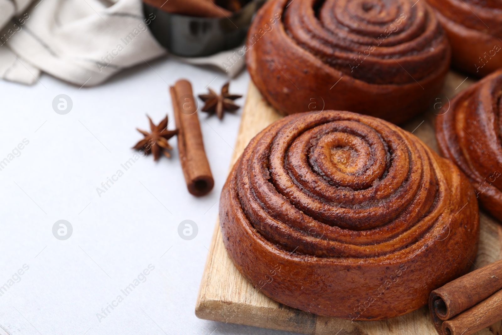 Photo of Delicious cinnamon roll buns on light table, closeup