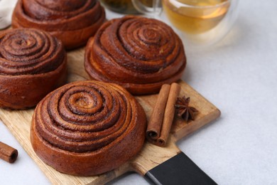 Photo of Delicious cinnamon roll buns on light table, closeup