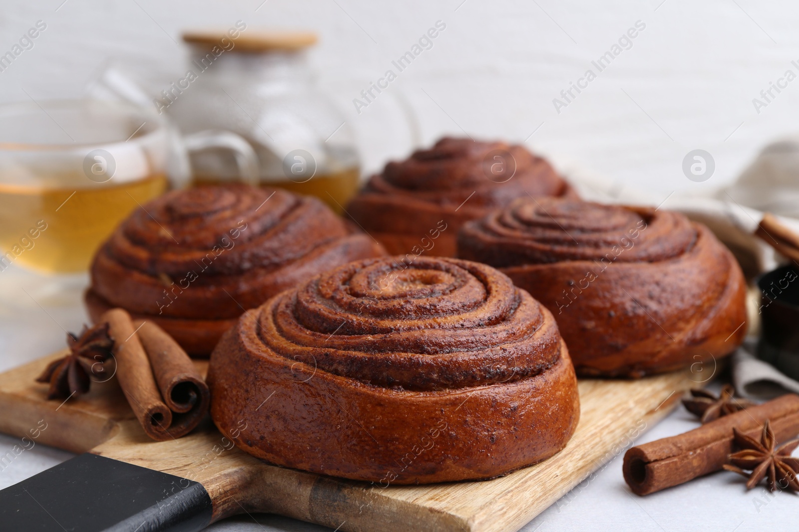 Photo of Delicious cinnamon roll buns on light table, closeup