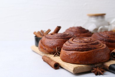 Photo of Delicious cinnamon roll buns on light table, closeup. Space for text