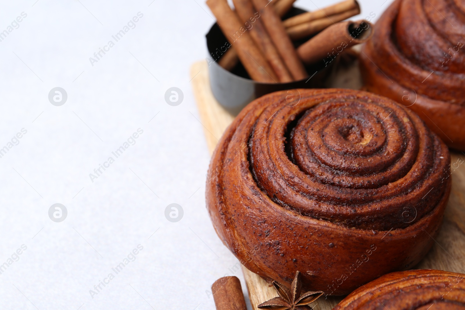 Photo of Delicious cinnamon roll buns on light table, closeup. Space for text