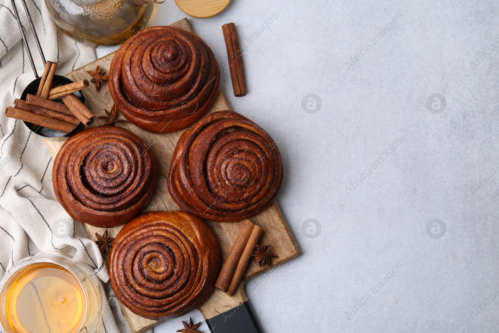 Photo of Delicious cinnamon roll buns and tea on light table, flat lay. Space for text