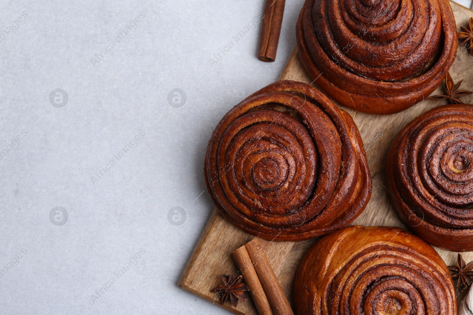 Photo of Delicious cinnamon roll buns on light table, flat lay. Space for text