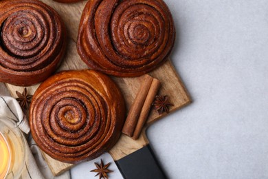 Photo of Delicious cinnamon roll buns on light table, flat lay