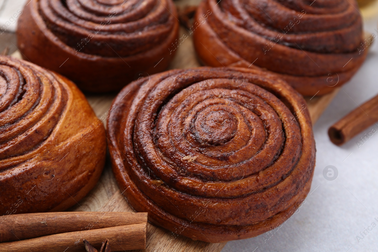 Photo of Delicious cinnamon roll buns on light table, closeup