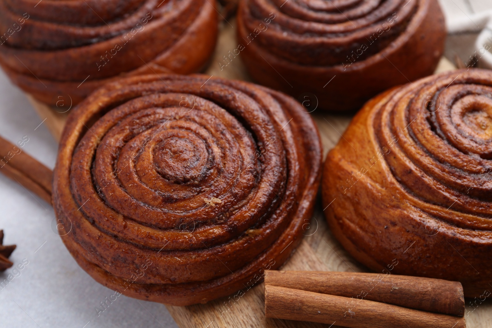 Photo of Delicious cinnamon roll buns on light table, closeup