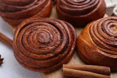 Photo of Delicious cinnamon roll buns on light table, closeup