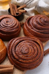 Photo of Delicious cinnamon roll buns on light table, closeup