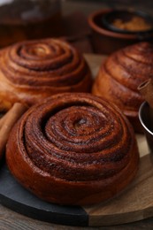 Photo of Delicious cinnamon roll buns on wooden table, closeup