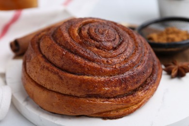 Photo of Delicious cinnamon roll bun on white table, closeup