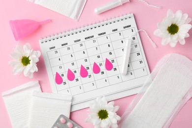 Photo of Flat lay composition with calendar and menstrual products on pink background