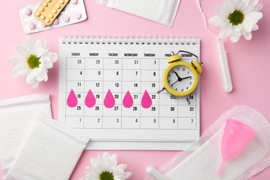 Photo of Flat lay composition with calendar and menstrual products on pink background