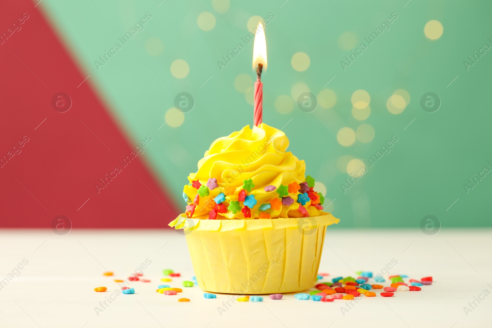 Photo of Tasty cupcake with burning candle on color background with blurred lights