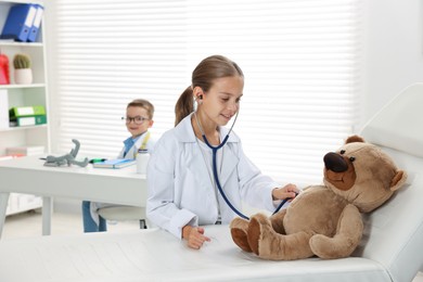 Photo of Little boy and girl with toy pretending to be doctors indoors