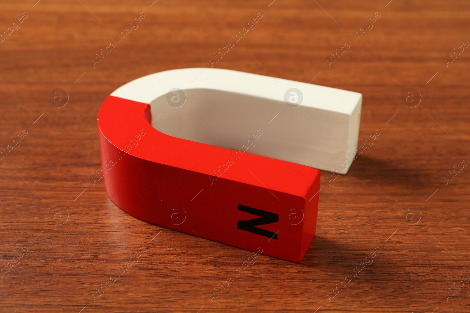 Photo of One horseshoe magnet on wooden table, closeup