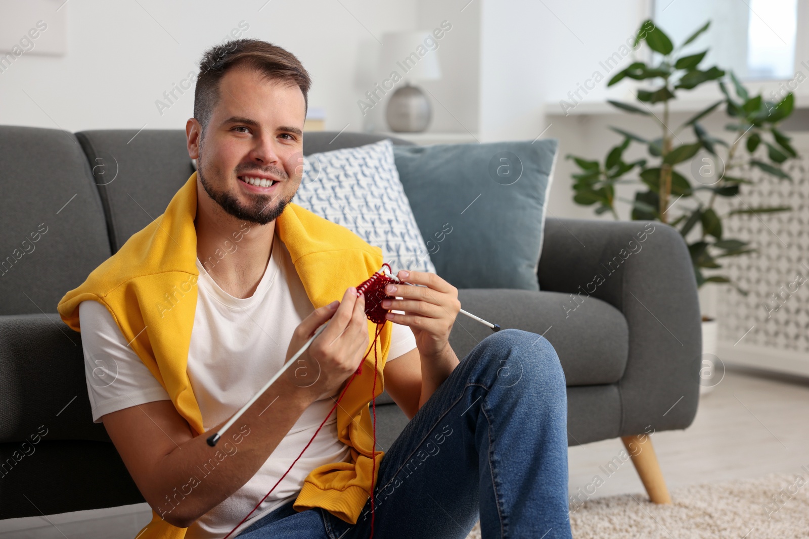 Photo of Man knitting with needles on floor at home