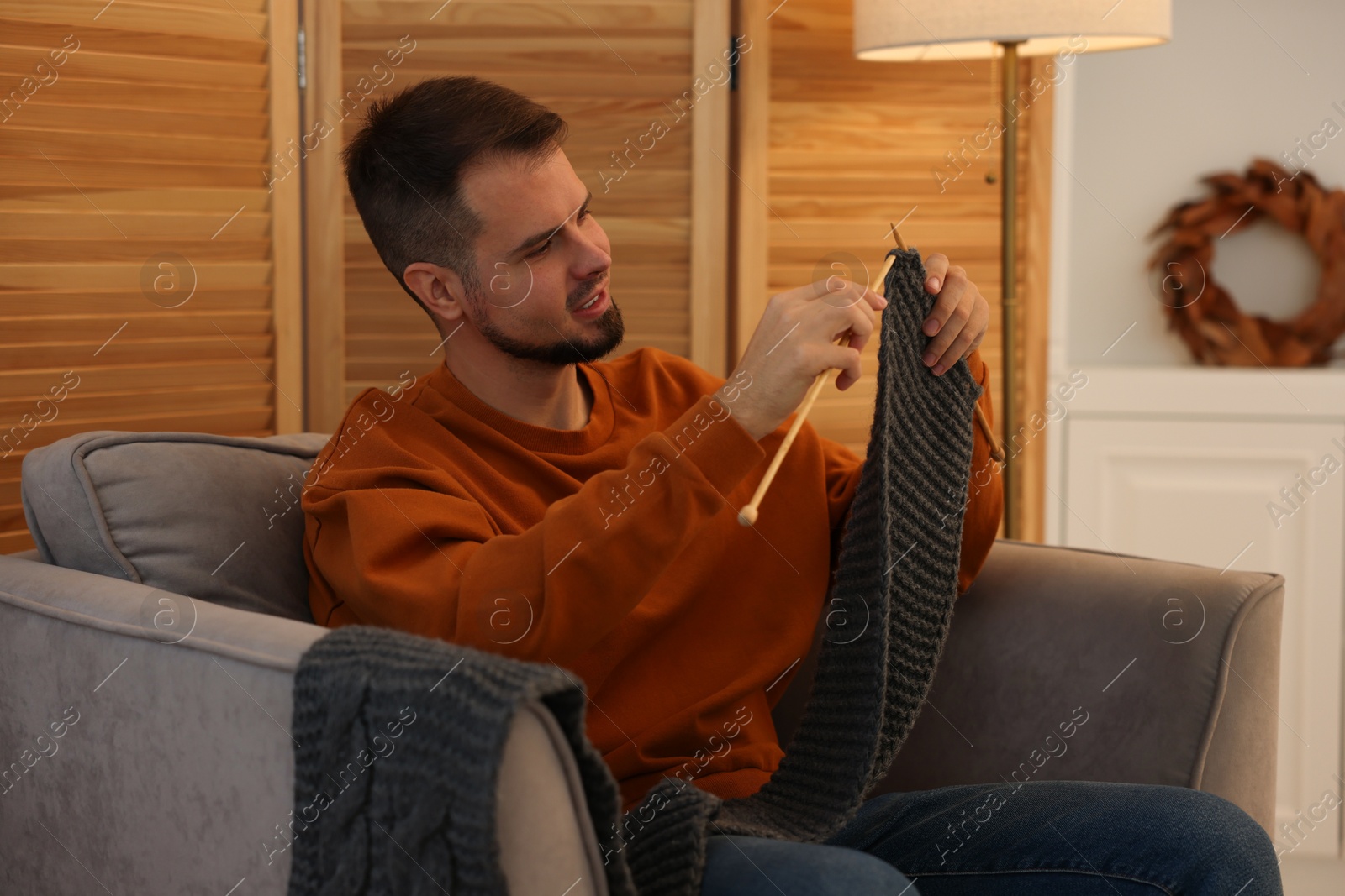 Photo of Man knitting with needles in armchair at home