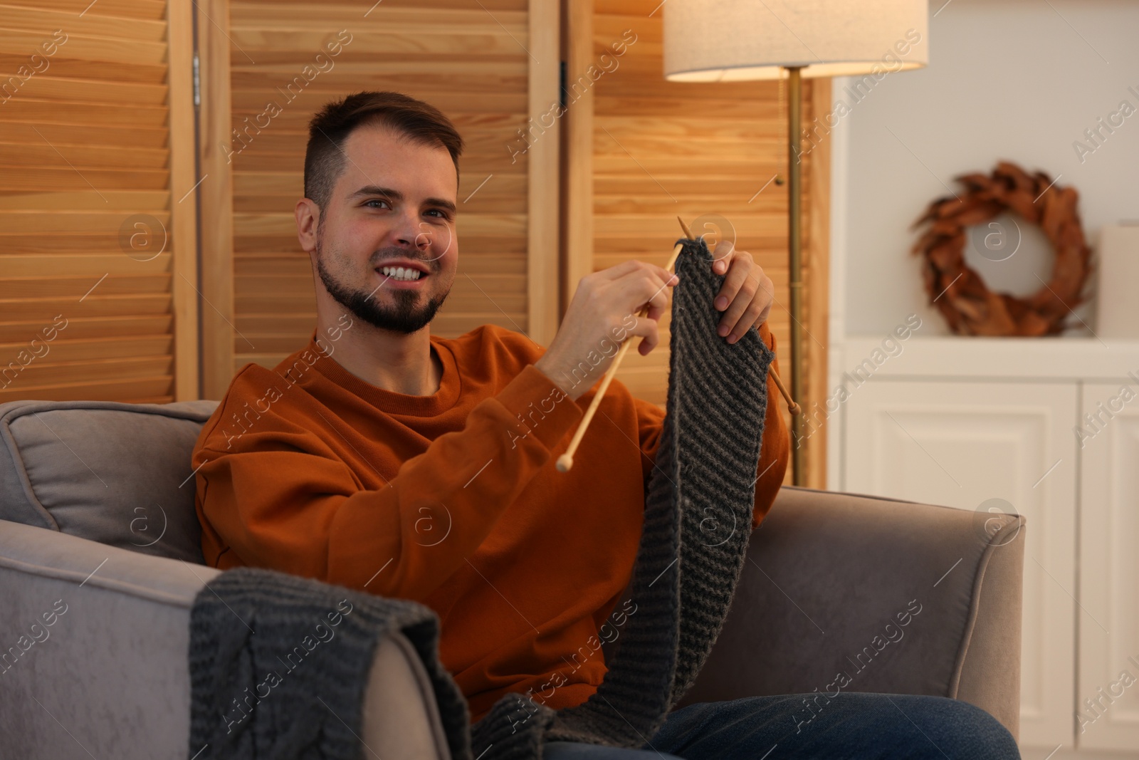 Photo of Man knitting with needles in armchair at home