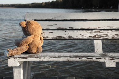 Photo of Lonely teddy bear on bench near river