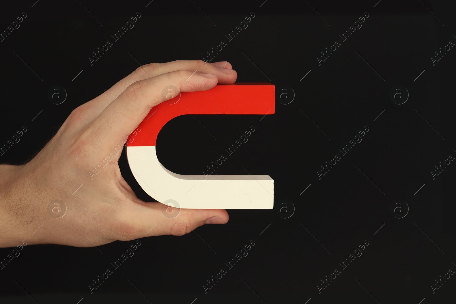 Photo of Man holding horseshoe magnet on dark background, closeup. Space for text