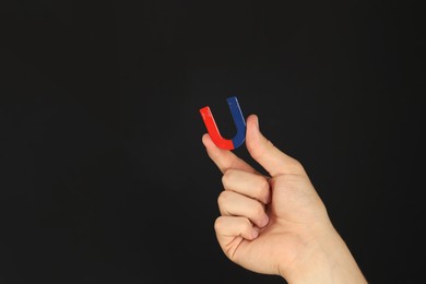 Photo of Man holding horseshoe magnet on dark background, closeup. Space for text