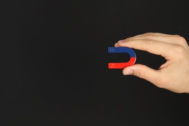 Photo of Man holding horseshoe magnet on dark background, closeup. Space for text