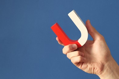 Photo of Man holding horseshoe magnet on blue background, closeup. Space for text