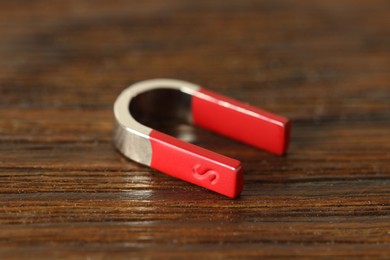 Photo of One horseshoe magnet on wooden table, closeup