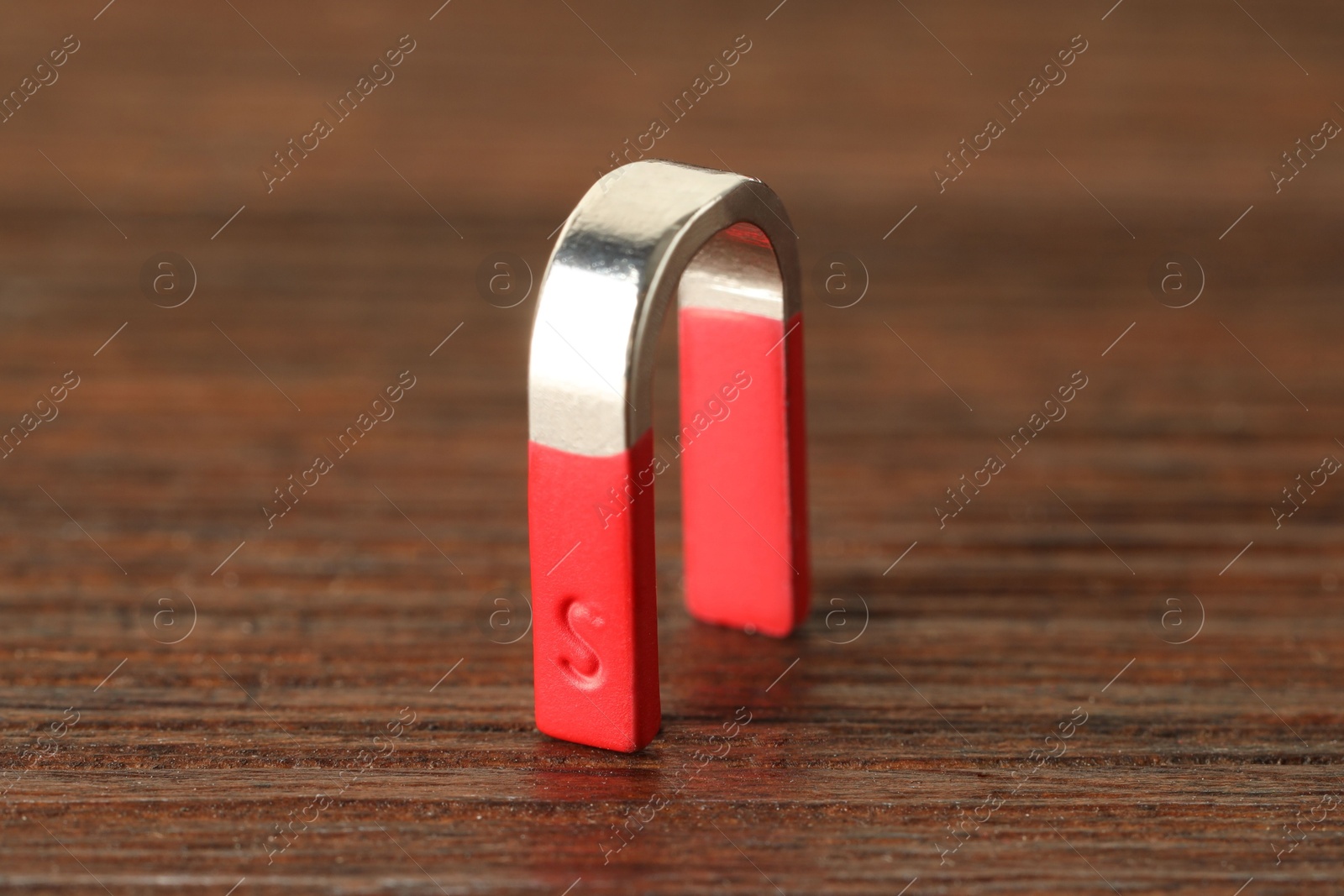 Photo of One horseshoe magnet on wooden table, closeup