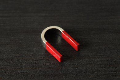 Photo of One horseshoe magnet on black wooden table, closeup